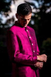 ARUN Silk Sherwani Jacket in Side view-man wearing ARUN sherwani jacket in wine raw silk with gold buttons in front of a dark background