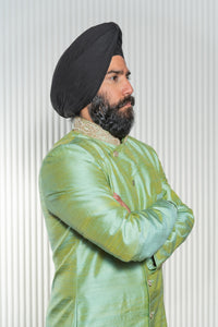 Side view- man wearing an Asymmetrical Sherwani Jacket in Sage Green with pearl collar detailing standing in front of a white background 