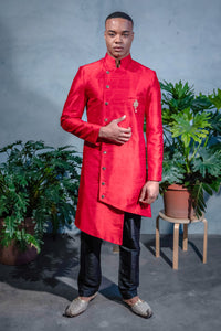 Front view- man wearing an Asymmetrical red Sherwani Jacket with a Mandarin Collar paired with black pajama pants 