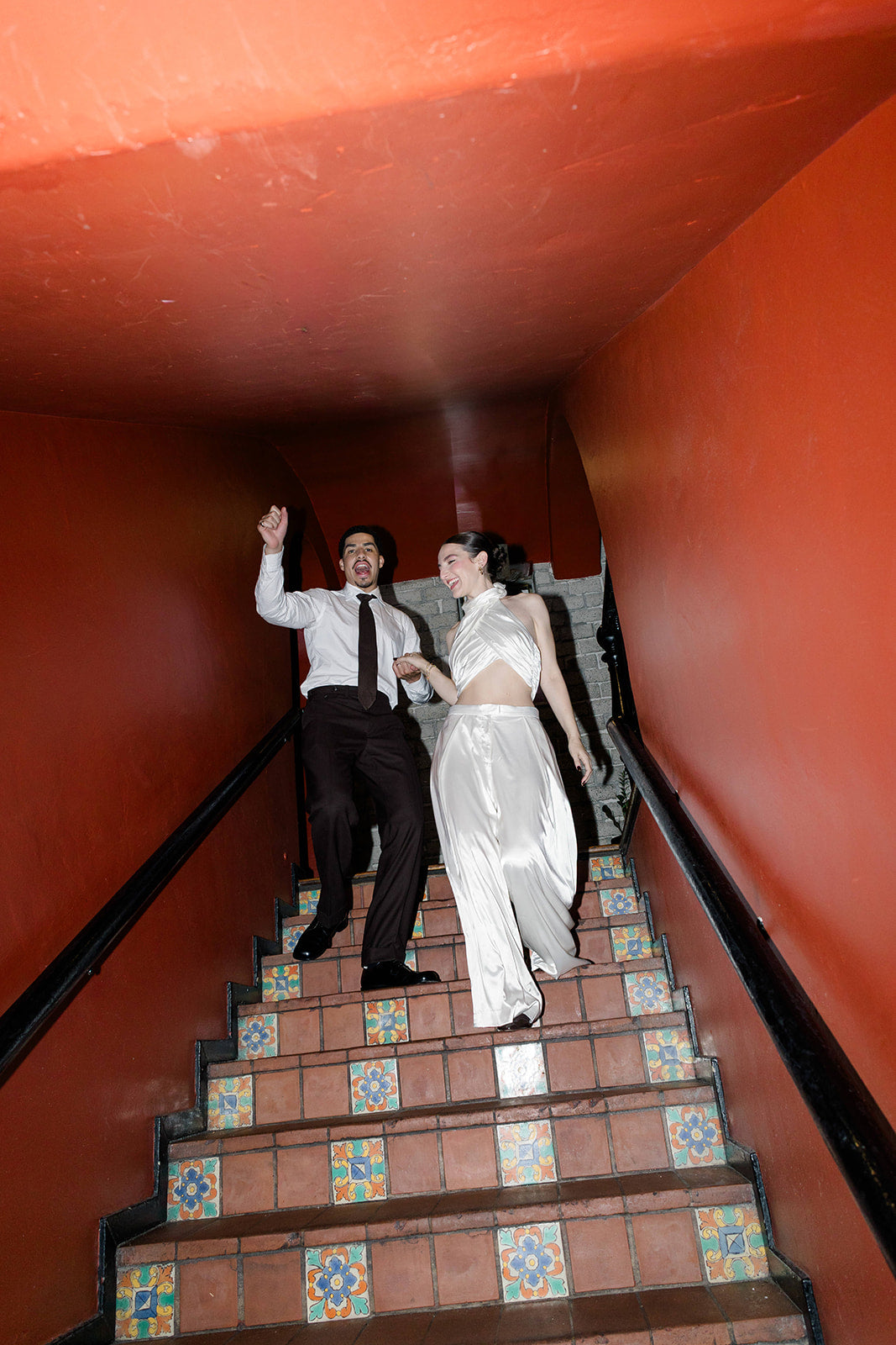 Bride Gracie walking down steps at Republique in a custom silky two-piece reception look by Harleen Kaur with Husband Marcus Scribner