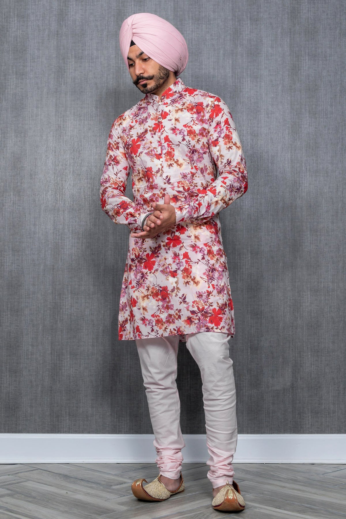 front-facing man wearing MANISH red floral print cotton kurta with light pink pajama pants and a light pink turban in front of a gray simple background