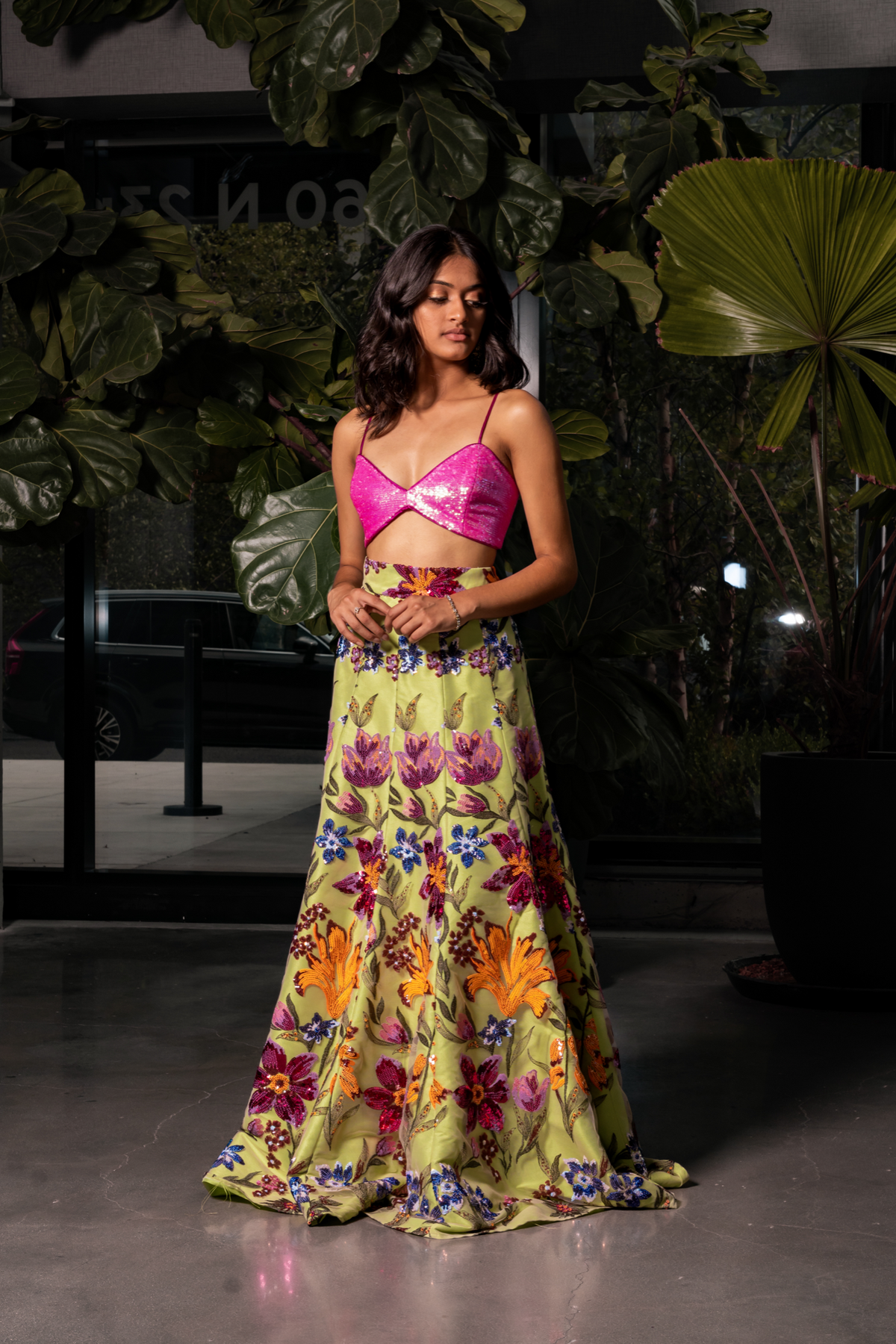model posing in a high waisted, lime green floral sequin gabriella lehenga skirt. Styled with a neon iridescent pink sequin bralette top.